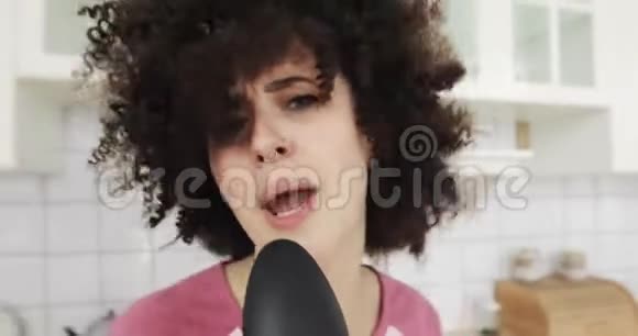 用勺子作为麦克风看镜头在厨房唱歌的女孩肖像视频的预览图