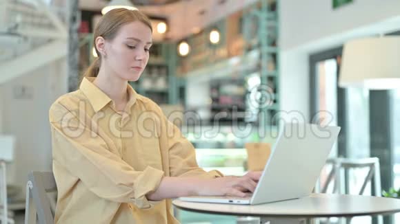 年轻女子在咖啡厅看镜头的笔记本电脑使用视频的预览图