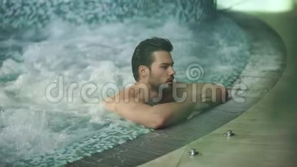 帅哥在按摩浴缸里休息迷人的男人在按摩浴缸中放松视频的预览图