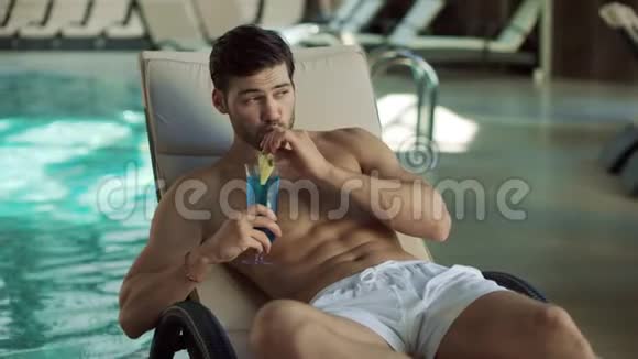 在游泳池附近喝鸡尾酒的人的肖像性感的家伙在休息室调情视频的预览图