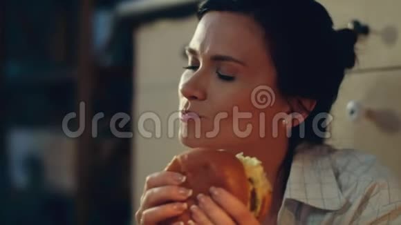 饿女孩在地板上吃汉堡年轻女子在家喝红酒视频的预览图