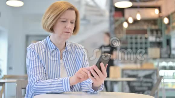 创意老女人在咖啡厅丢失智能手机视频的预览图