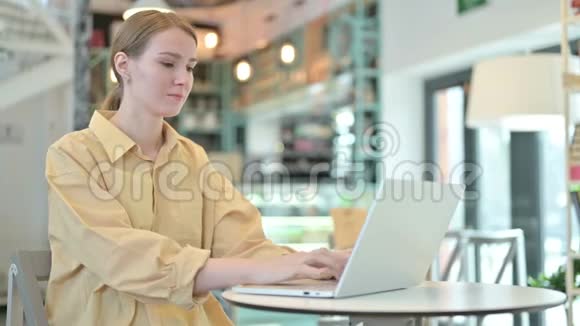 青年妇女在咖啡厅用手提电脑竖起大拇指视频的预览图