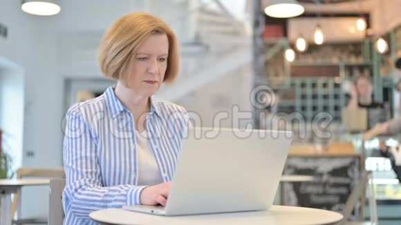 在咖啡厅使用笔记本电脑的具有攻击性的创意的老女人视频的预览图