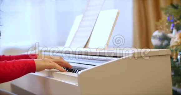 女学生或女学生或专业钢琴家在圣诞假期用漂亮的白色钢琴演奏古典音乐视频的预览图