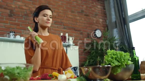 女人在厨房品尝新鲜芹菜快乐的黑发烹饪健康的食物视频的预览图