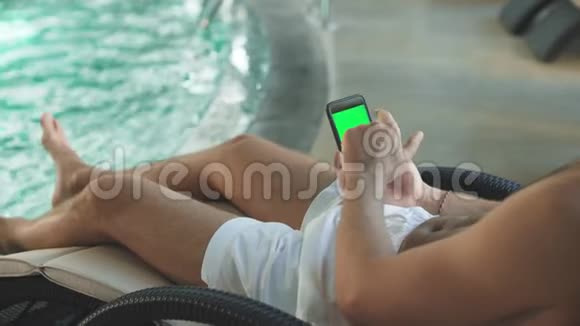 在酒店特写男士双手拿着带有绿色屏幕的手机视频的预览图