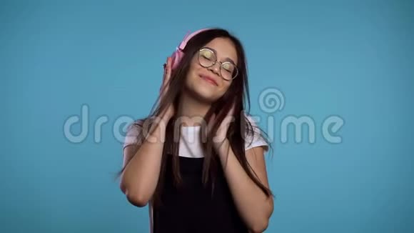 年轻漂亮的亚洲女孩在演播室里带着耳机跳舞开心地笑着视频的预览图