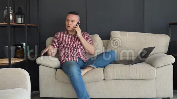 沙发上的男人在智能手机上说话视频的预览图