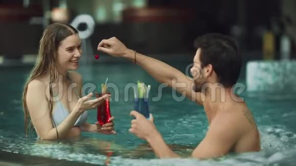 有魅力的情侣在泳池里玩一对快乐的夫妇喝着鸡尾酒视频的预览图