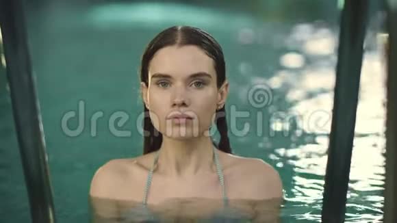 站在豪华酒店游泳池里的性感女人的肖像湿漉漉的女人摆姿势视频的预览图