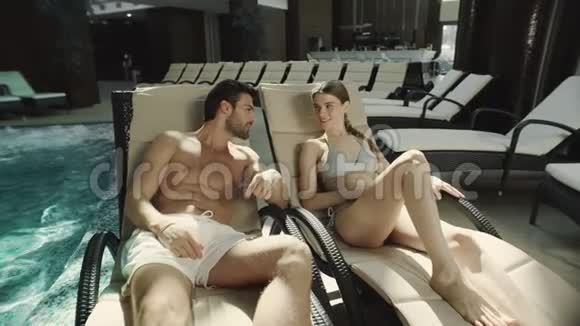 年轻夫妇躺在游泳池边男人和女人在水疗中心放松视频的预览图
