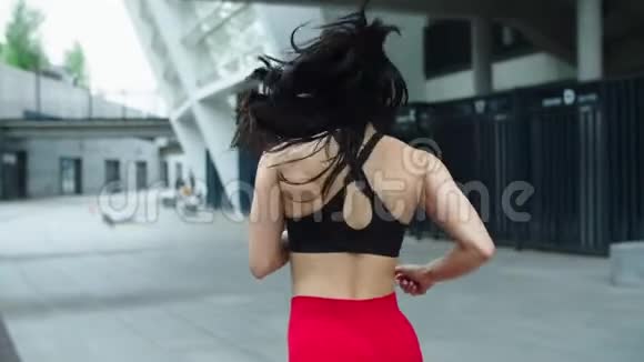 女运动员在户外跑步在城市街道慢跑的运动女孩的后景视频的预览图