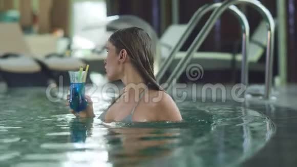 性感的女人在豪华游泳池里喝鸡尾酒女人喝酒视频的预览图
