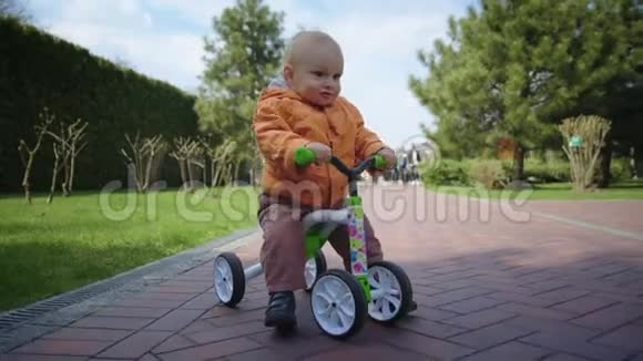 小男孩在公园骑自行车笑有趣的孩子骑自行车慢动作视频的预览图