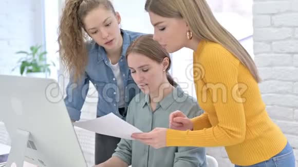 专注于年轻女性设计师阅读文件和使用桌面视频的预览图