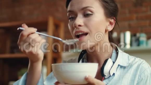 女人在厨房里吃带牛奶的玉米片早餐吃麦片的女孩视频的预览图
