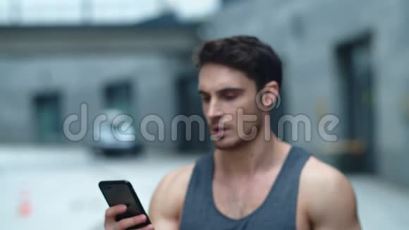 特写运动员男子在街上看智能手机微笑的男人在读视频的预览图