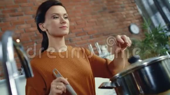优雅的女人用勺子搅拌汤小女孩闻到烧锅里的食物视频的预览图
