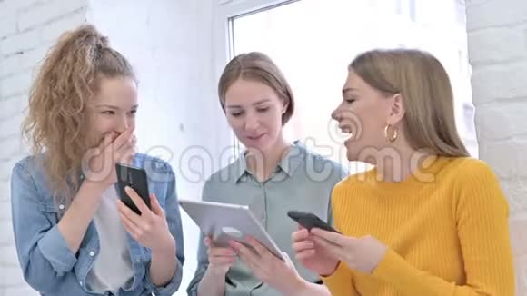 快乐的年轻女性使用智能手机和平板电脑视频的预览图