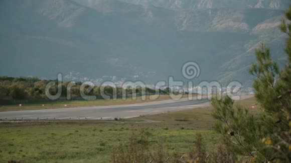 一架小型飞机坐在山脉背景上的跑道上视频的预览图