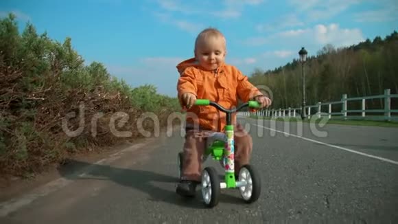 微笑的幼儿在公园骑自行车骑自行车看相机的有趣男孩视频的预览图