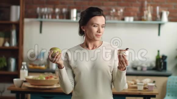 女人在厨房里选择苹果和蛋糕女孩选择水果饮食视频的预览图