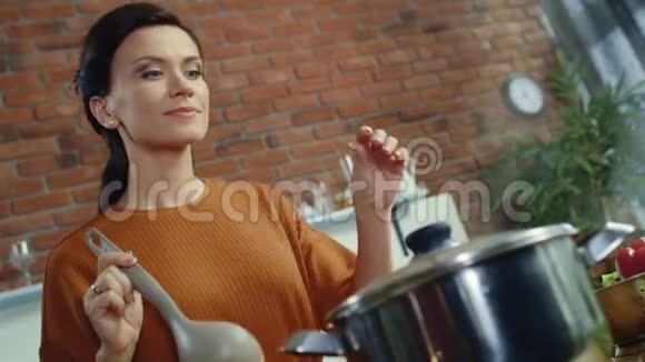 厨房里闻着热汤的女人家庭主妇在家厨房做饭视频的预览图