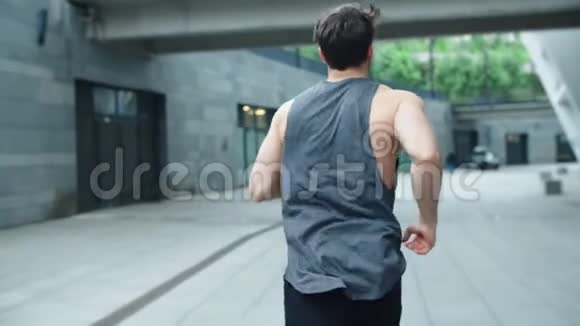 适合男子在户外缓慢运动运动员男子训练跑的后视图视频的预览图