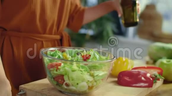 女人的手把橄榄油倒入沙拉家庭主妇烹饪季节性蔬菜视频的预览图