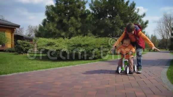 几个孩子在户外玩自行车哥哥推着男孩骑自行车视频的预览图