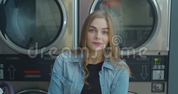 年轻微笑的美国女人站在自助洗衣店的肖像视频的预览图