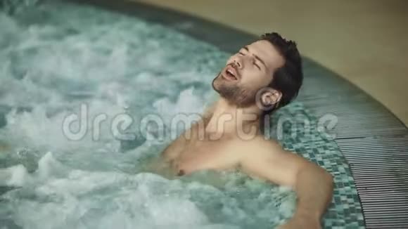 微笑的男人在室内按摩浴缸中放松性感男人在按摩浴缸里休息视频的预览图