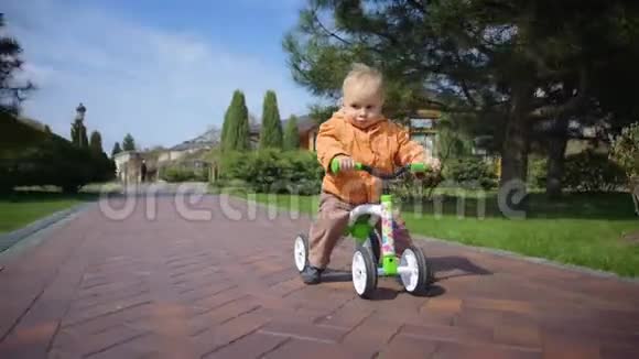 在春天公园骑自行车的小孩为室外摄像机摆姿势的有趣男孩视频的预览图