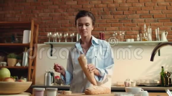年轻女子在木板上切割面包在家准备早餐的女孩视频的预览图