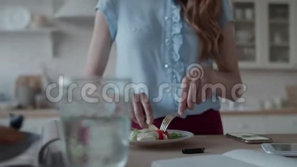 漂亮的女人在家里的厨房里吃午饭吃沙拉的女士视频的预览图