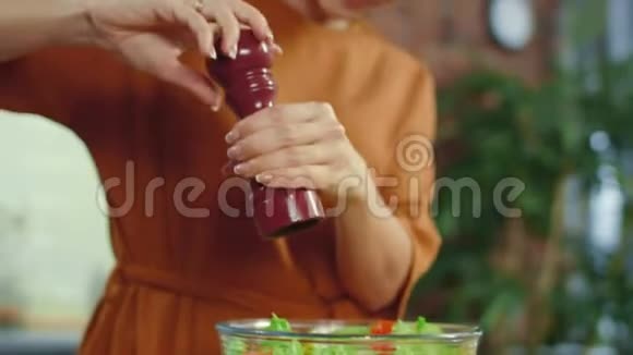 女孩在蔬菜沙拉中添加香料女人在厨房里调味蔬菜视频的预览图
