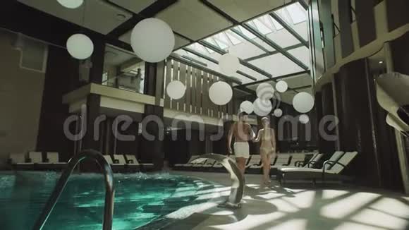 欢乐情侣漫步室内游泳池幸福的一对牵手视频的预览图