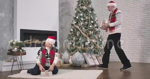 快乐的白种人老两口在一起过除夕微笑的白种人来到圣诞树前视频的预览图