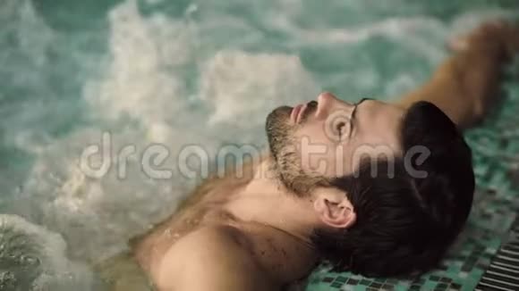 特写性感男人享受按摩浴缸水疗在泳池里放松的帅哥画像视频的预览图