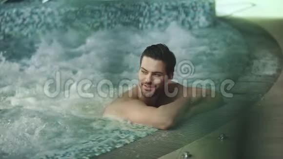 快乐的人在按摩浴缸里休息微笑的男人在温泉酒店打招呼视频的预览图
