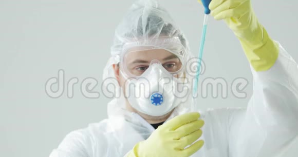 医生将蓝色溶液从吸管滴入玻璃管冠状病毒大流行视频的预览图