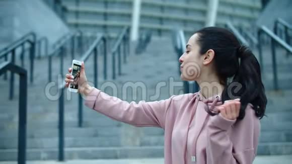 快乐的女人在外面的智能手机上拍照运动女人拍自拍照片视频的预览图