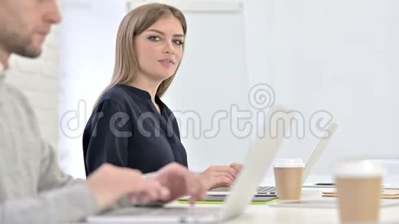美丽的创意女性在笔记本电脑上工作在镜头前微笑视频的预览图