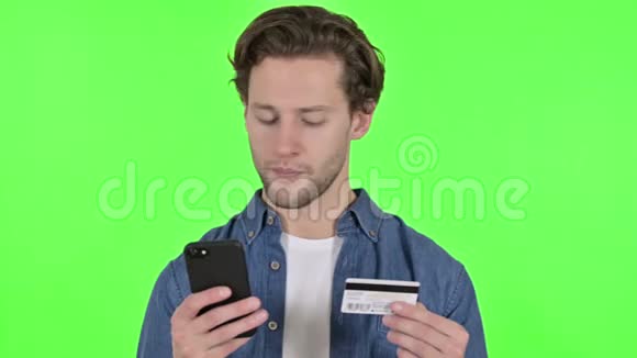 年轻人在智能手机上使用绿色铬钥匙的信用卡记录视频的预览图