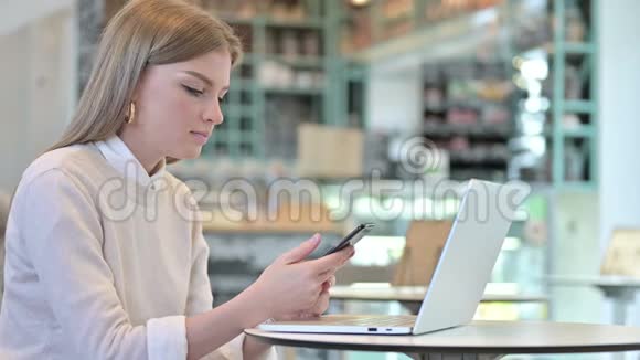 咖啡馆里年轻女子使用智能手机视频的预览图