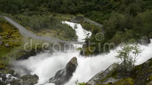 群山中的一座桥旁边有一个强大的瀑布视频的预览图