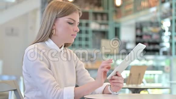 年轻女子在咖啡馆的平板电脑上庆祝成功视频的预览图