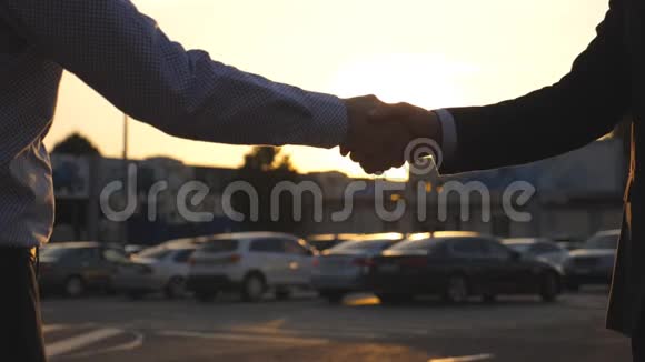 男性手经销商给予钥匙的汽车客户与太阳耀斑在背景商人的手臂穿过汽车钥匙视频的预览图