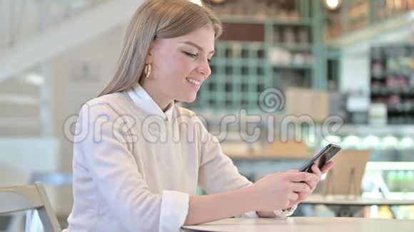 咖啡馆里使用智能手机的职业年轻女性视频的预览图